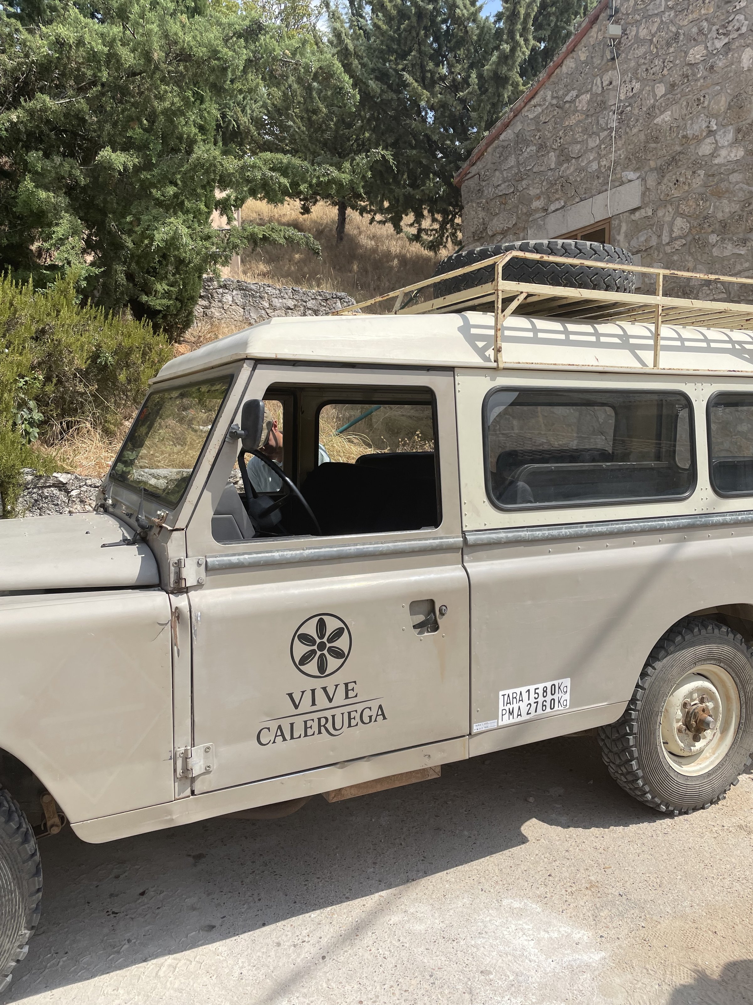 Land Rover clásico de Vive Caleruega frente a una casa de piedra en Caleruega, Burgos